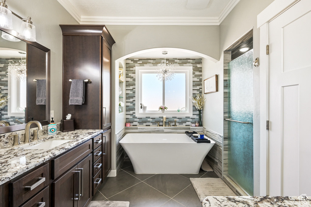 Full bath with tile patterned flooring, vanity, a chandelier, a freestanding bath, and healthy amount of natural light