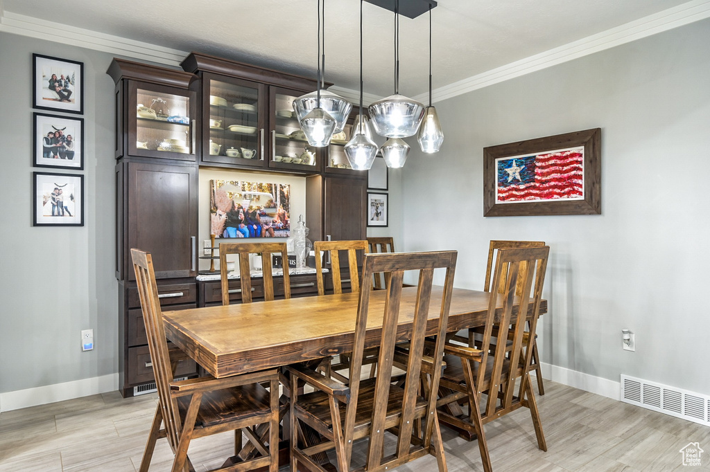 Dining area featuring crown molding and light wood-type flooring