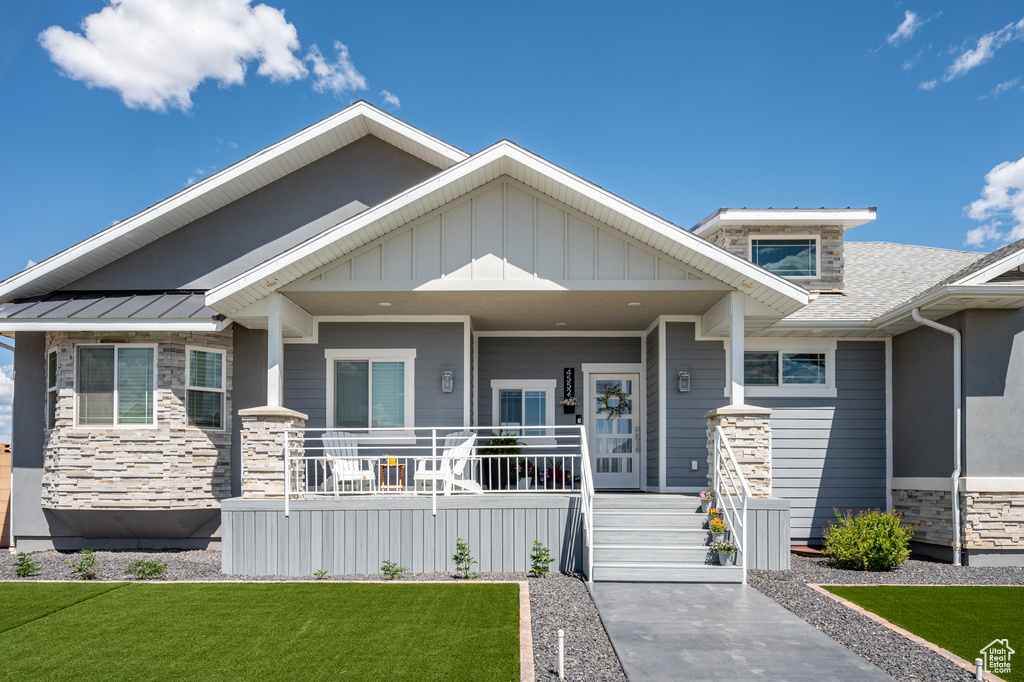 Craftsman-style home with stone siding, covered porch, and a front yard
