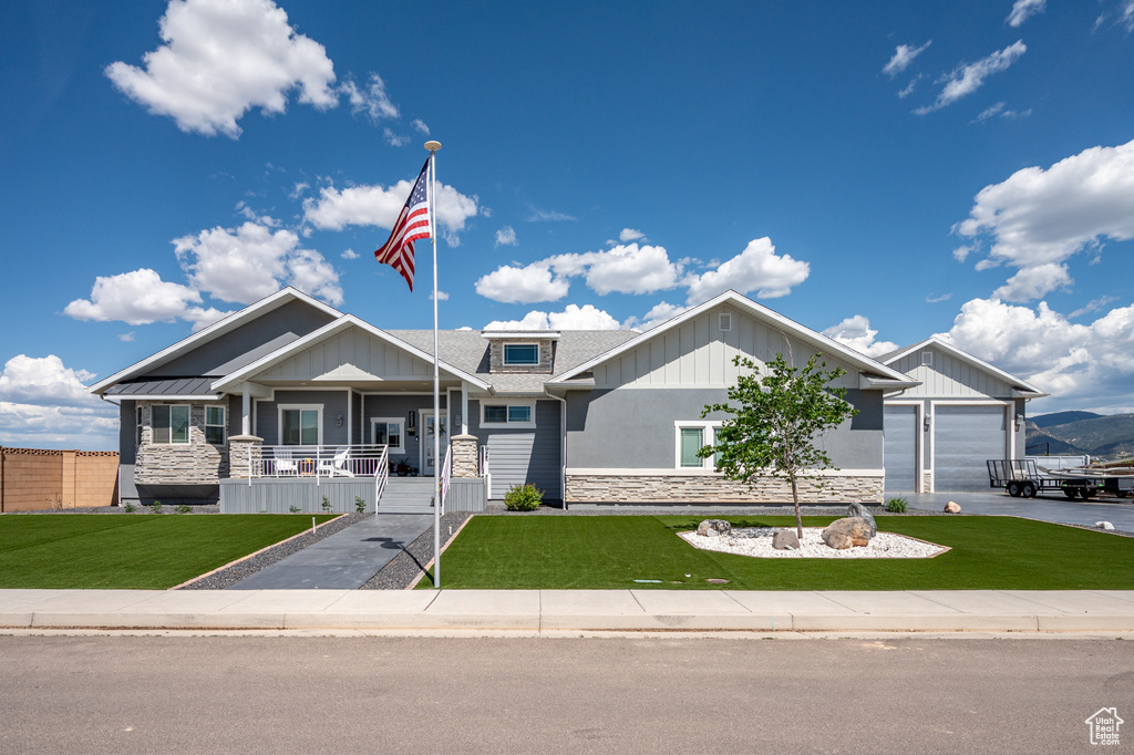 Craftsman house featuring stone siding, covered porch, and a front lawn