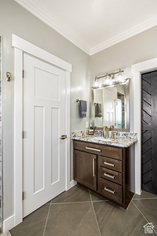 Bathroom with crown molding, tile patterned floors, and vanity