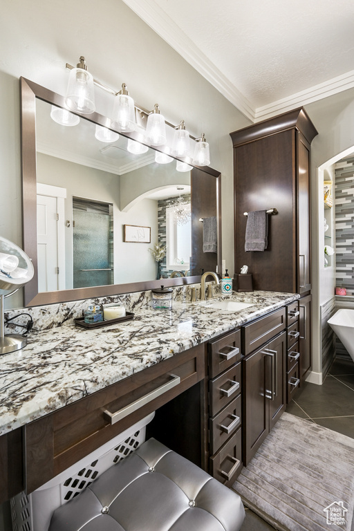 Bathroom featuring ornamental molding, vanity, tile patterned floors, a soaking tub, and a chandelier