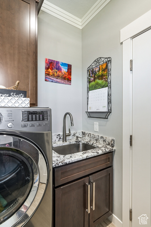 Washroom featuring washer / dryer, cabinet space, crown molding, and light wood-style floors
