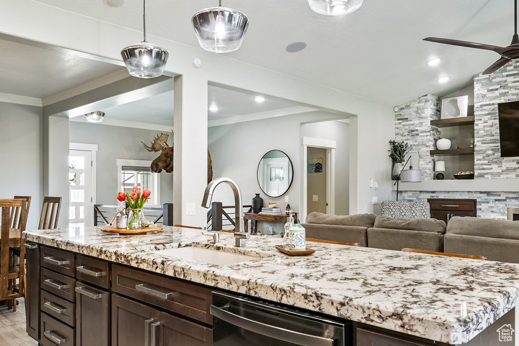 Kitchen featuring black dishwasher, a ceiling fan, light stone counters, open floor plan, and ornamental molding