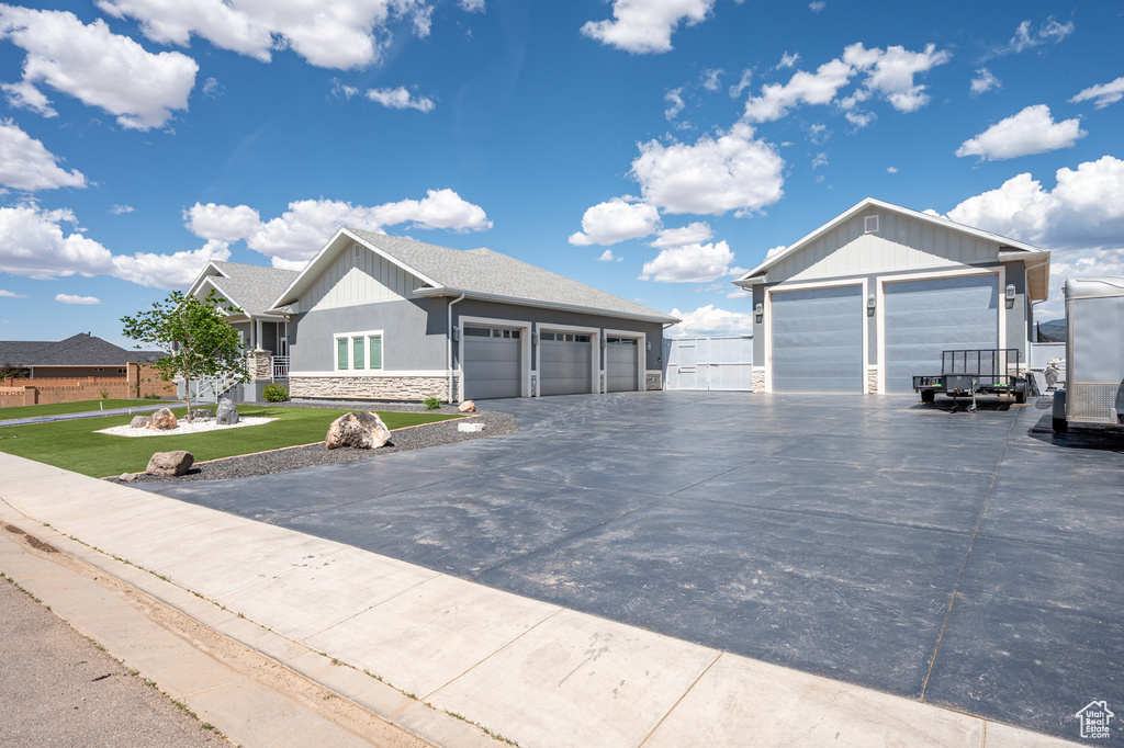 Ranch-style house with stone siding, a garage, a front lawn, and driveway