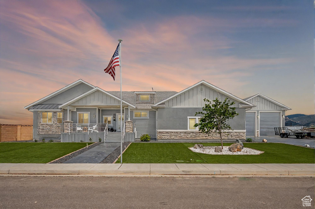 View of front of home featuring board and batten siding, a front yard, a porch, and stone siding
