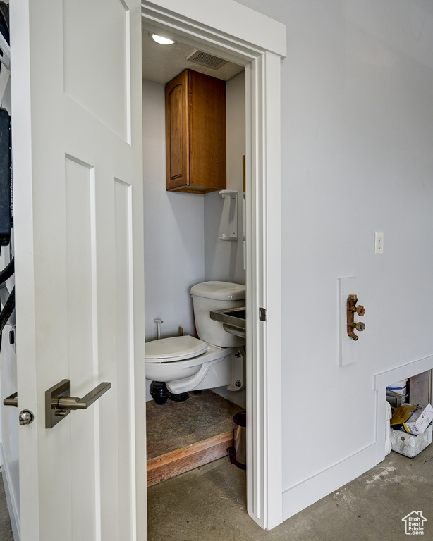 Bathroom featuring unfinished concrete floors and toilet