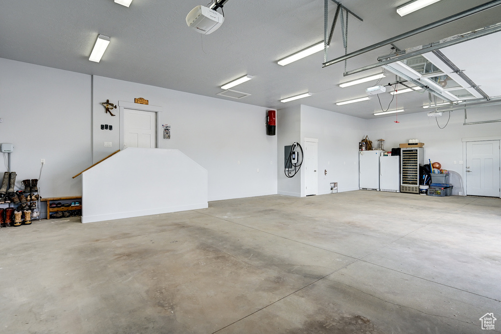 Garage featuring a garage door opener and freestanding refrigerator