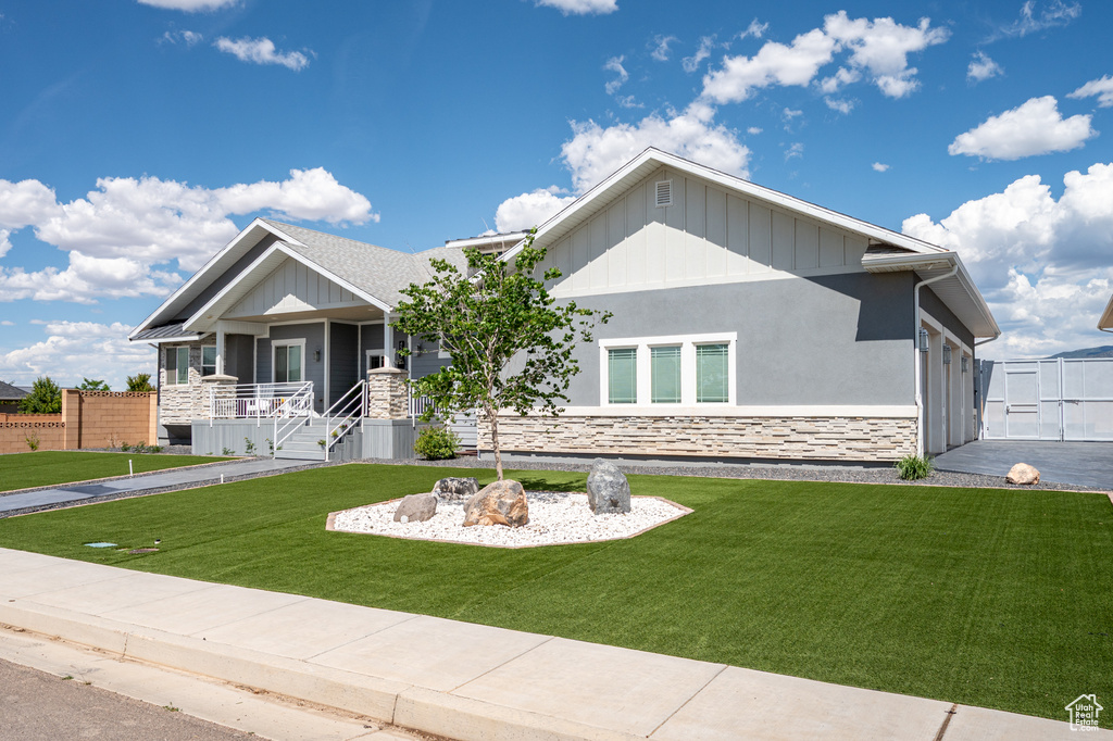 View of front of property featuring stone siding, a porch, board and batten siding, and stucco siding