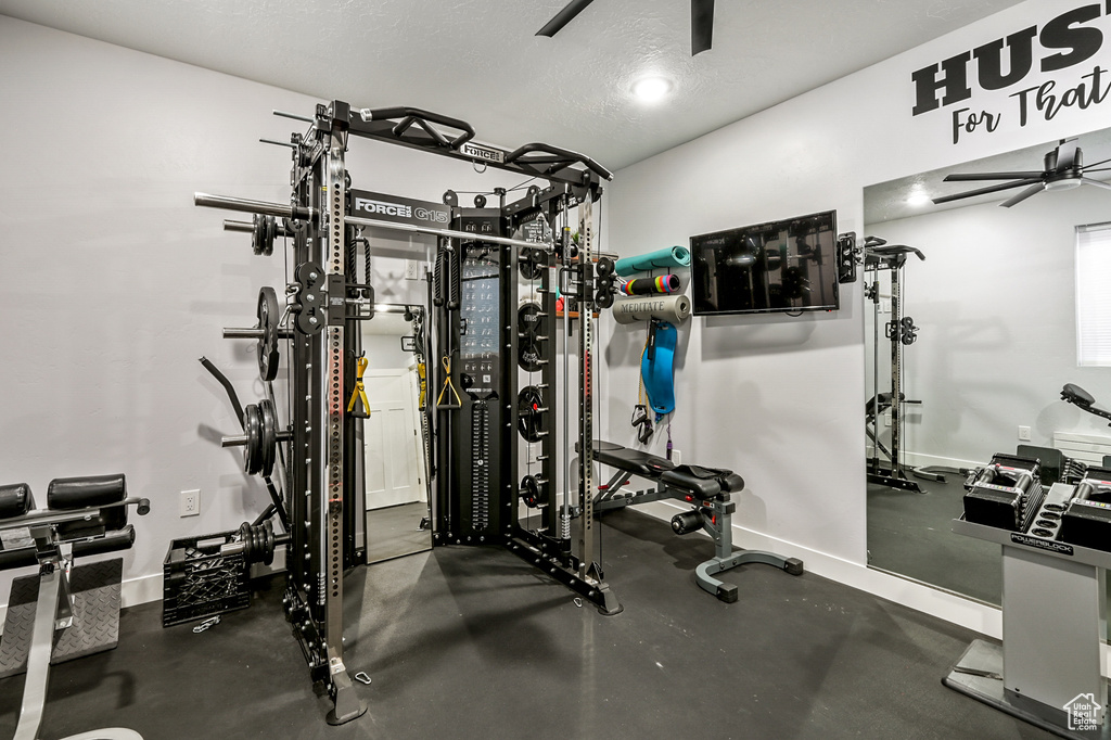 Workout area with a ceiling fan and baseboards