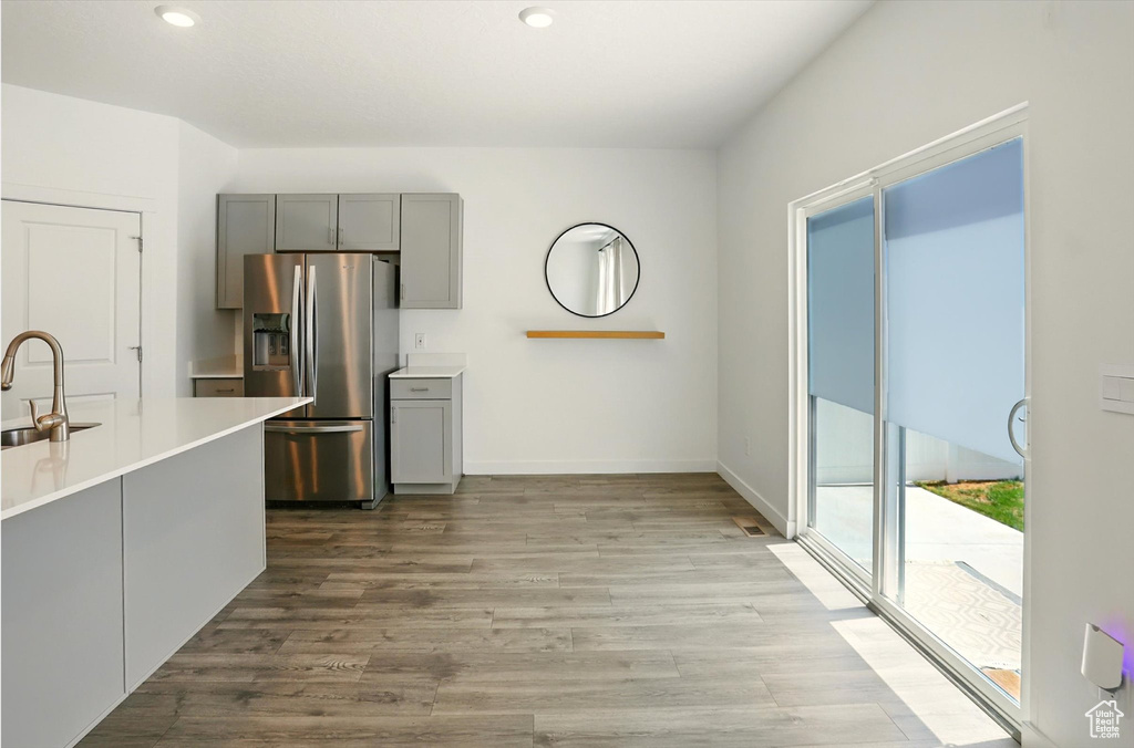 Kitchen with stainless steel fridge, gray cabinetry, wood finished floors, light countertops, and recessed lighting