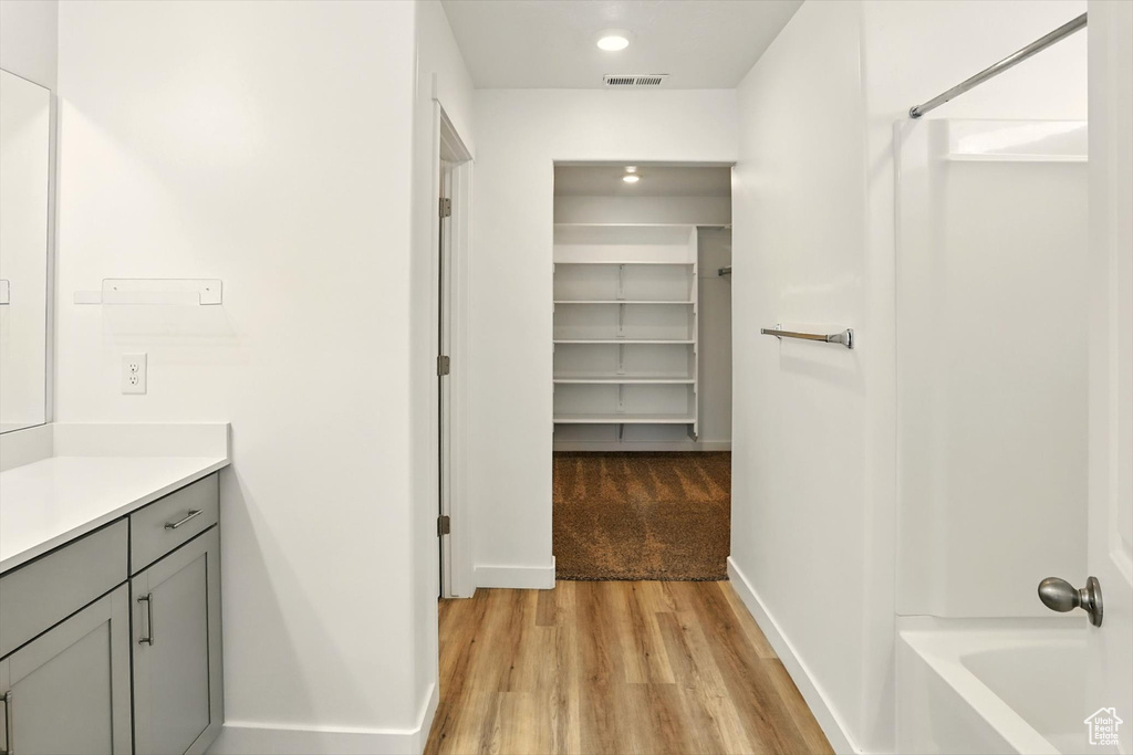 Full bathroom with vanity, wood finished floors, a spacious closet, recessed lighting, and shower / washtub combination