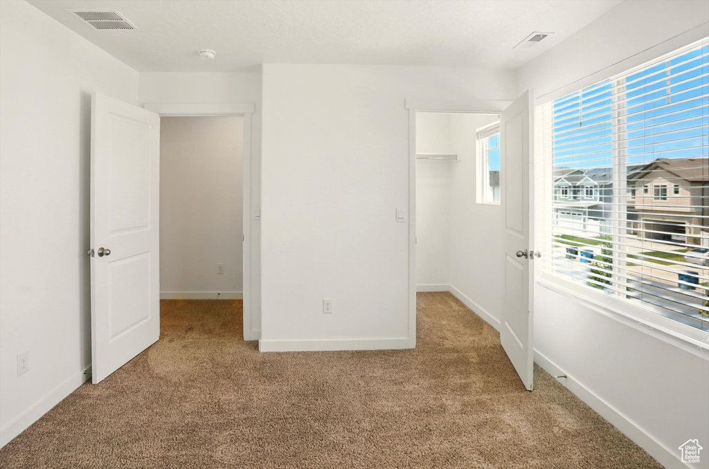 Unfurnished bedroom with light colored carpet and a spacious closet