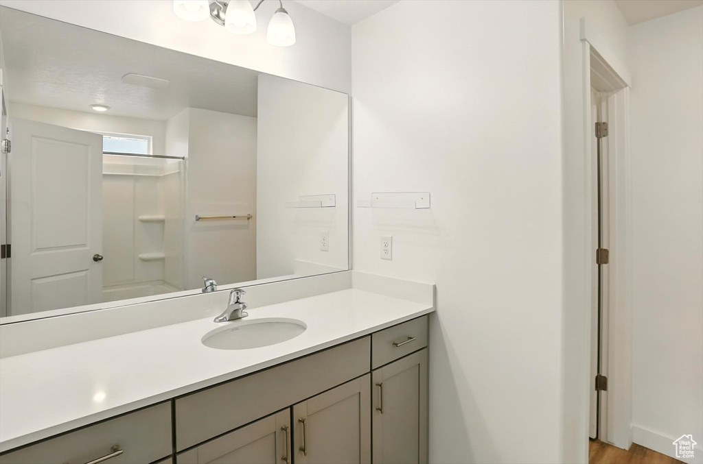 Bathroom with vanity, washtub / shower combination, and wood finished floors