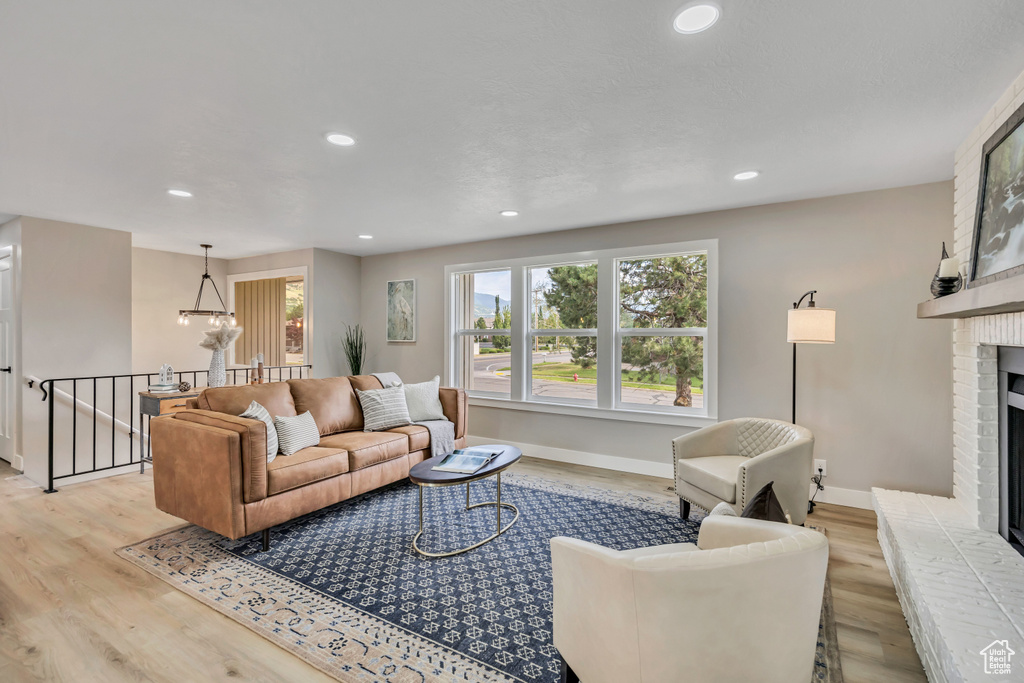 Living room featuring light wood-style flooring, a fireplace, recessed lighting, and a chandelier