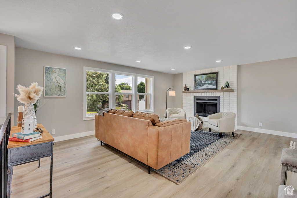 Living room with light wood finished floors, a fireplace, and recessed lighting
