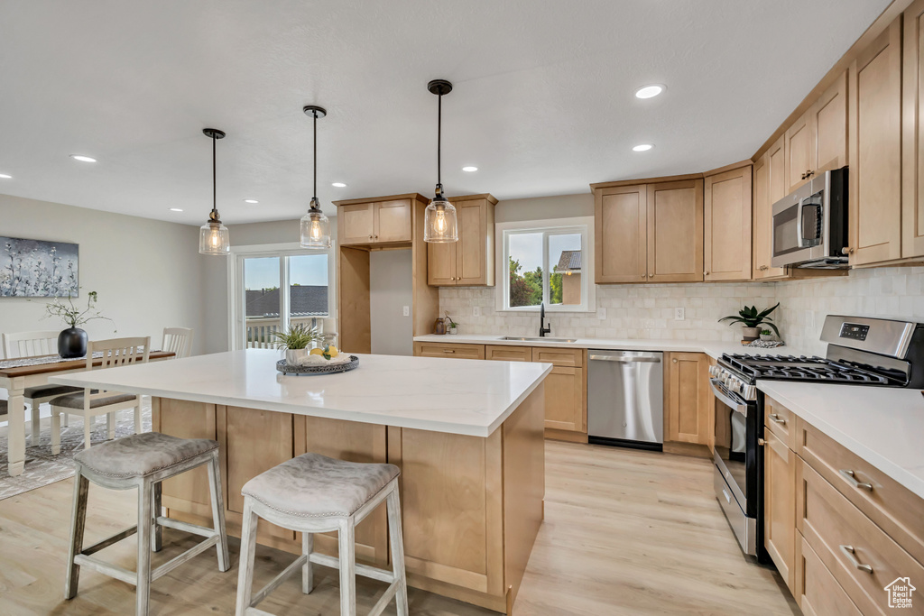 Kitchen featuring appliances with stainless steel finishes, plenty of natural light, a kitchen island, light wood-type flooring, and recessed lighting