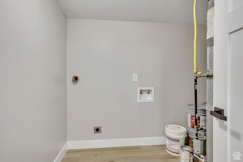 Laundry room with hookup for an electric dryer, washer hookup, wood finished floors, and a textured ceiling