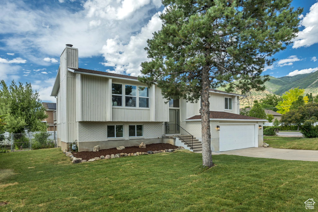 View of front of property featuring a chimney, driveway, a garage, a mountain view, and brick siding