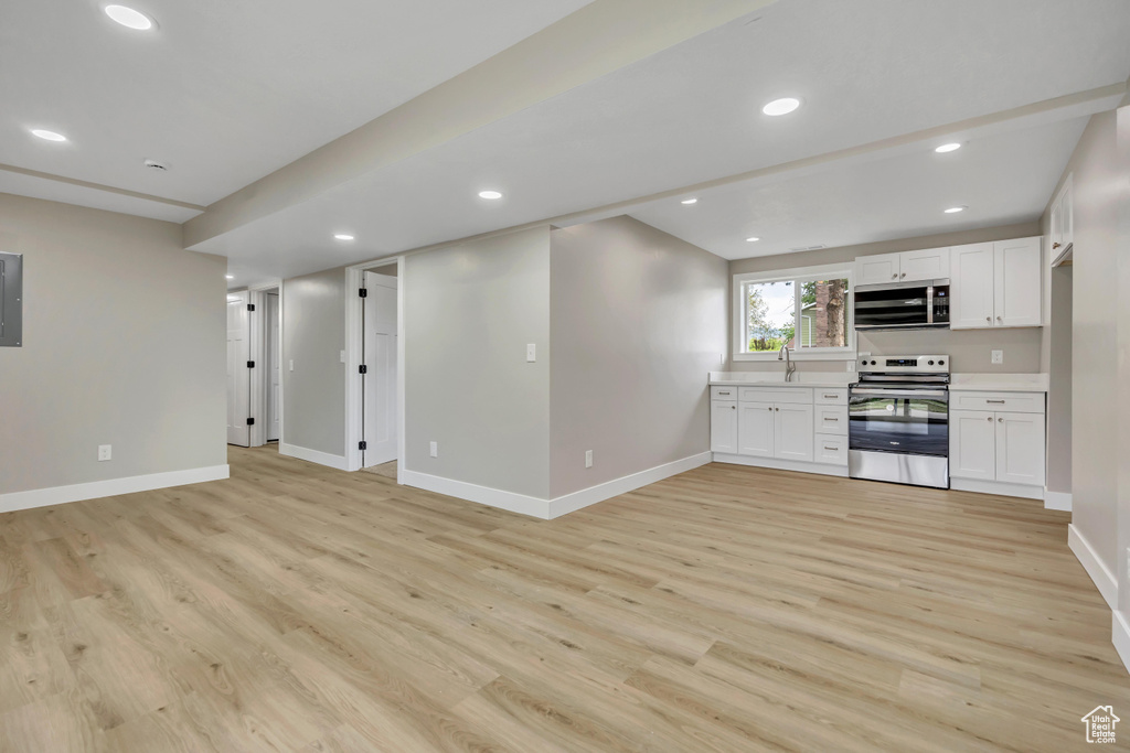 Unfurnished living room featuring light wood-type flooring, recessed lighting, and electric panel