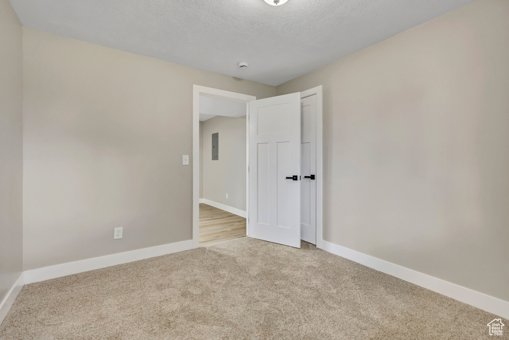 Unfurnished room with carpet floors, a textured ceiling, and electric panel