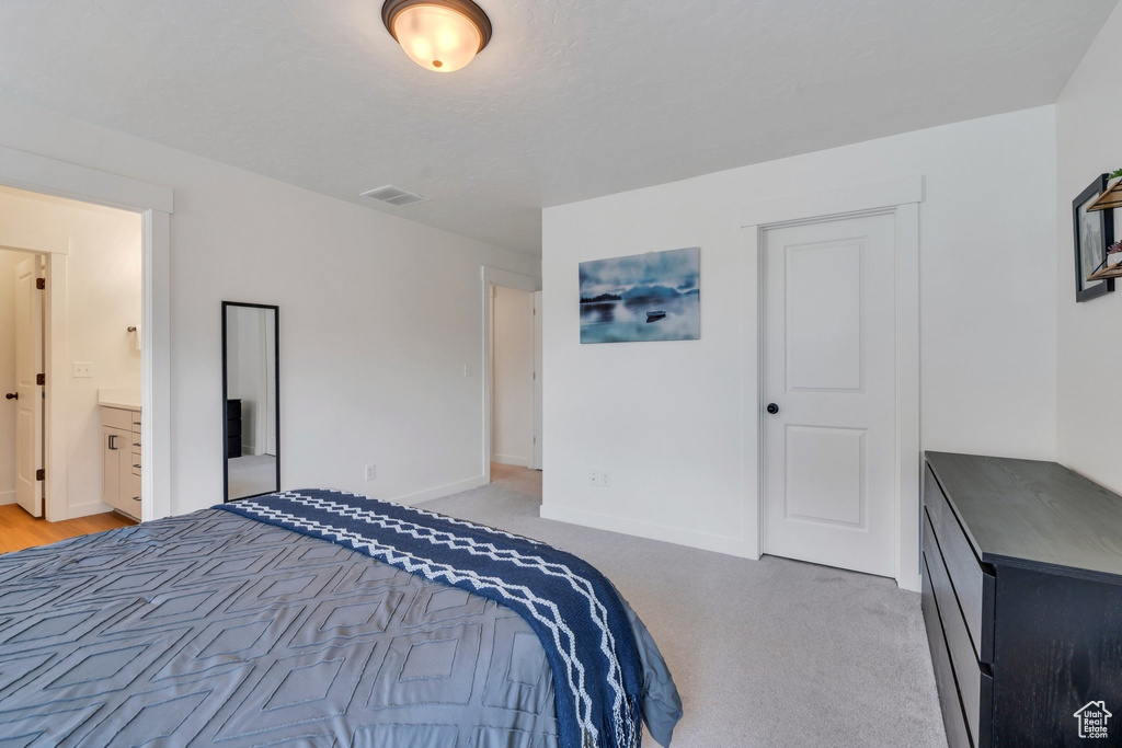 Bedroom featuring light carpet and ensuite bathroom