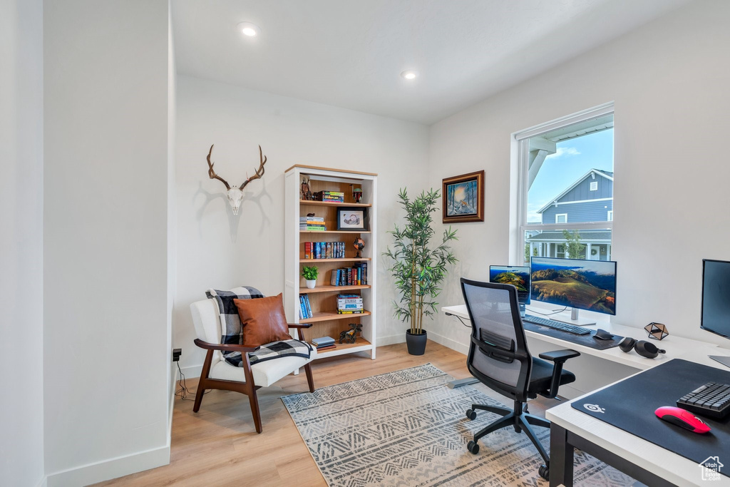 Office with light wood-style flooring and recessed lighting