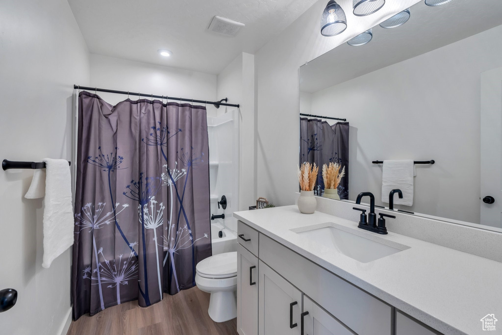 Full bathroom with wood finished floors, vanity, and shower / tub combo