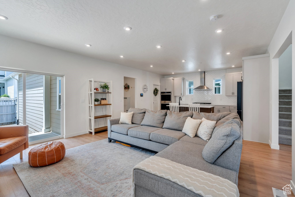 Living area featuring light wood finished floors, recessed lighting, and stairway