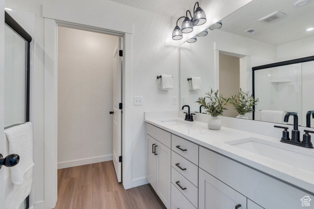 Full bath featuring double vanity, wood finished floors, and a shower stall
