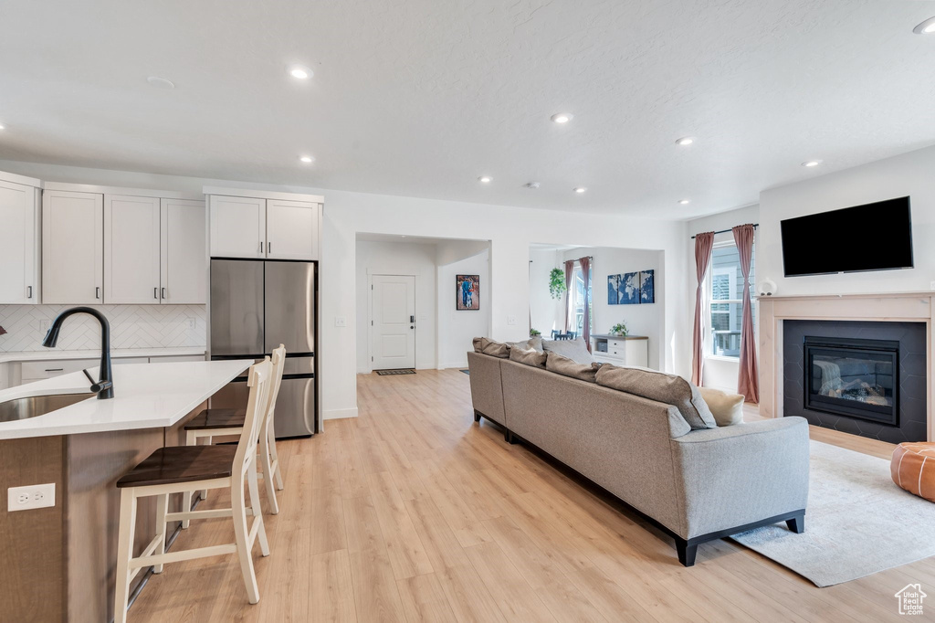 Living room with light wood-type flooring, recessed lighting, and a glass covered fireplace