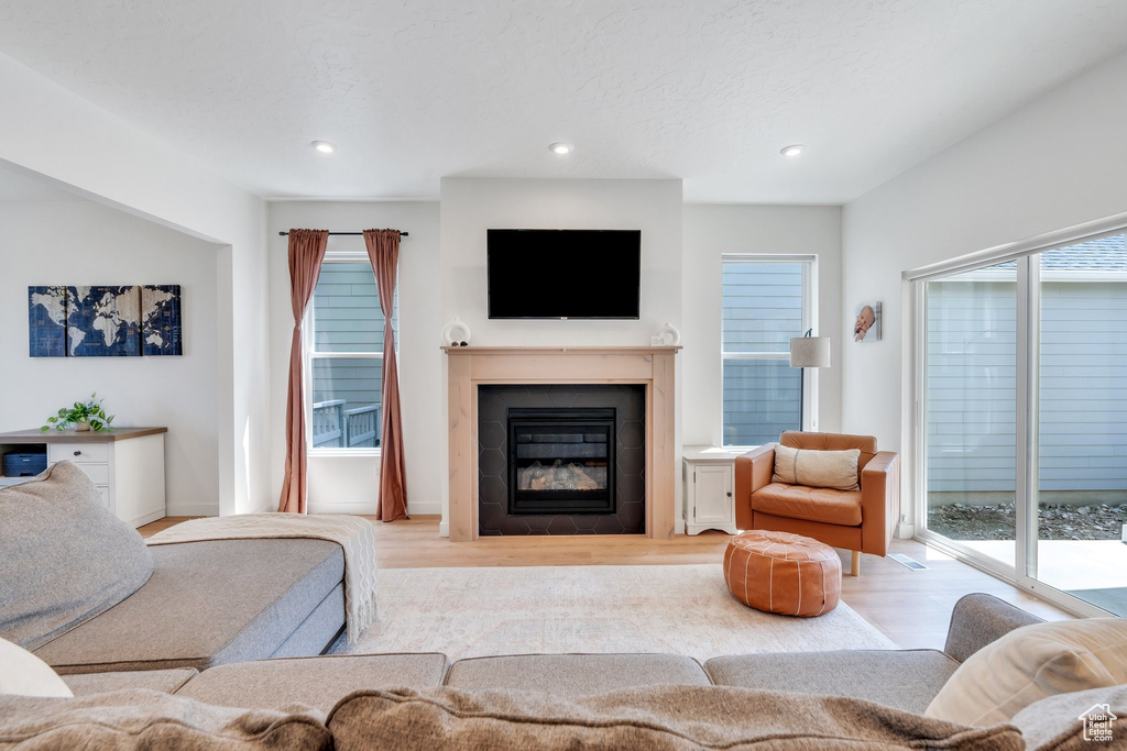 Living area featuring wood finished floors, a tile fireplace, plenty of natural light, and recessed lighting
