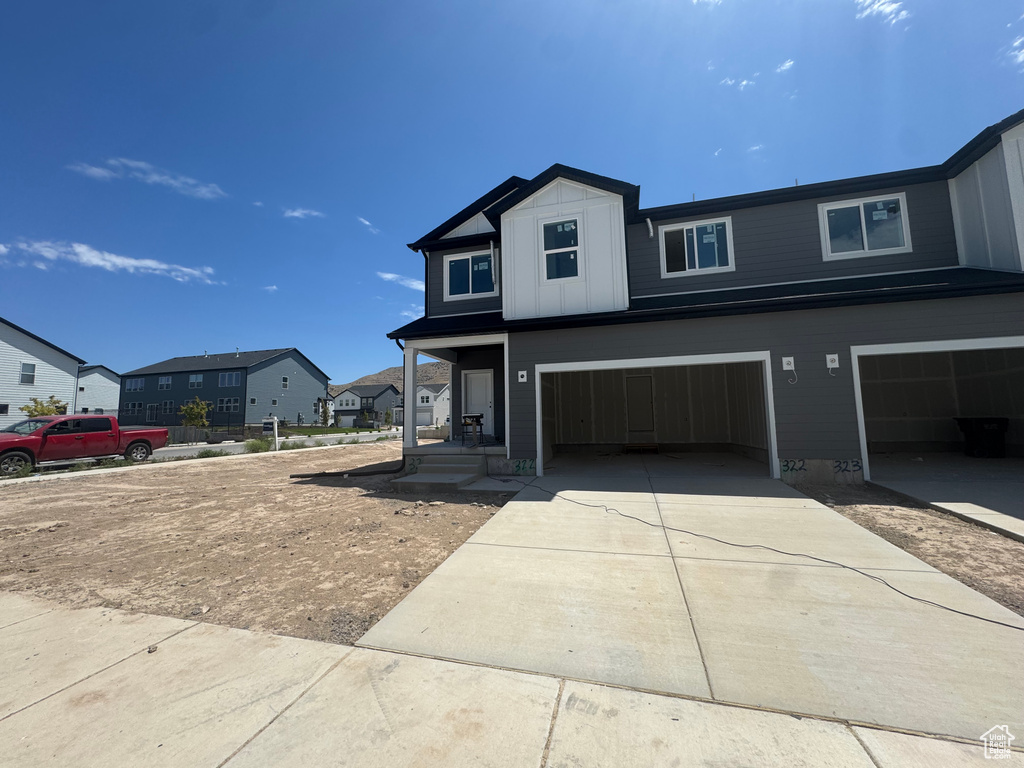 View of front of house with a garage, concrete driveway, and a residential view