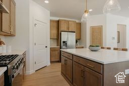 Kitchen with light countertops, light wood-style floors, a kitchen island, recessed lighting, and stainless steel range