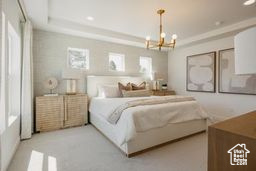 Bedroom featuring a chandelier and a raised ceiling