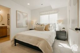Bedroom with light colored carpet and connected bathroom