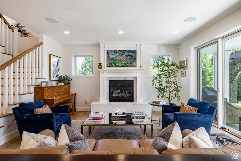 Living room with wood finished floors, a premium fireplace, stairs, and recessed lighting