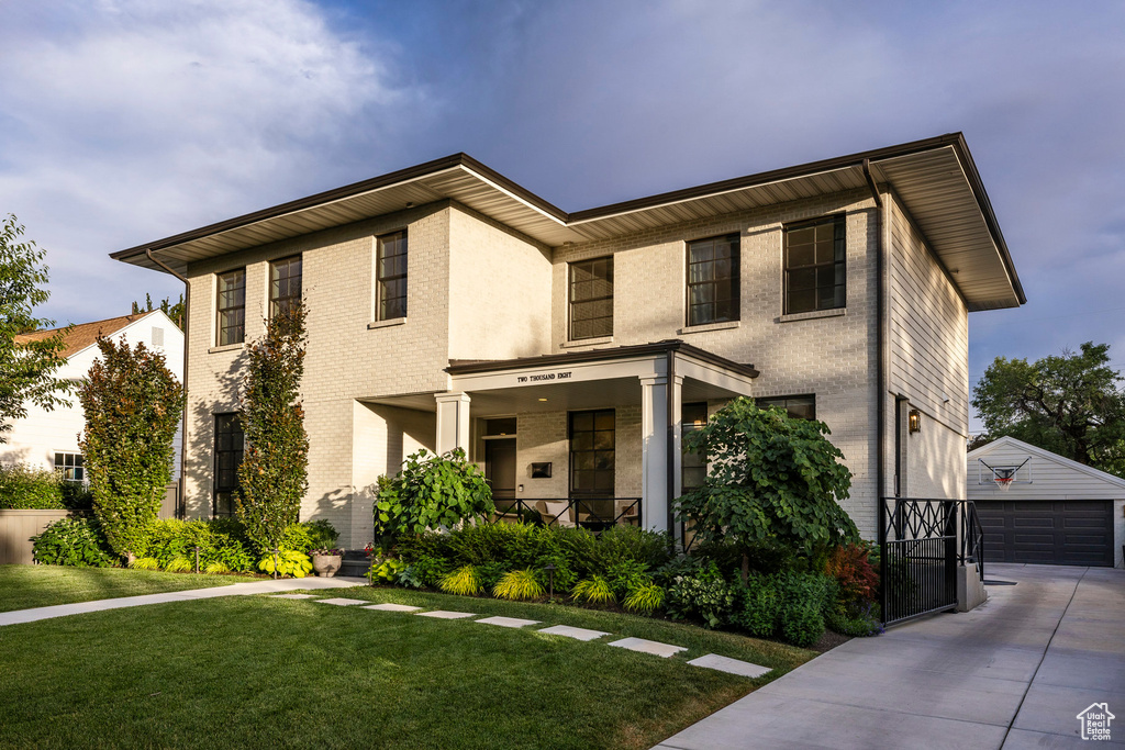 View of front of house featuring an outdoor structure, a front lawn, brick siding, a porch, and a garage