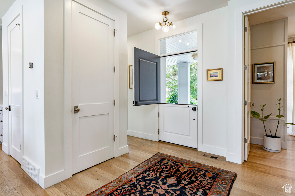Entryway featuring light wood-type flooring and a chandelier