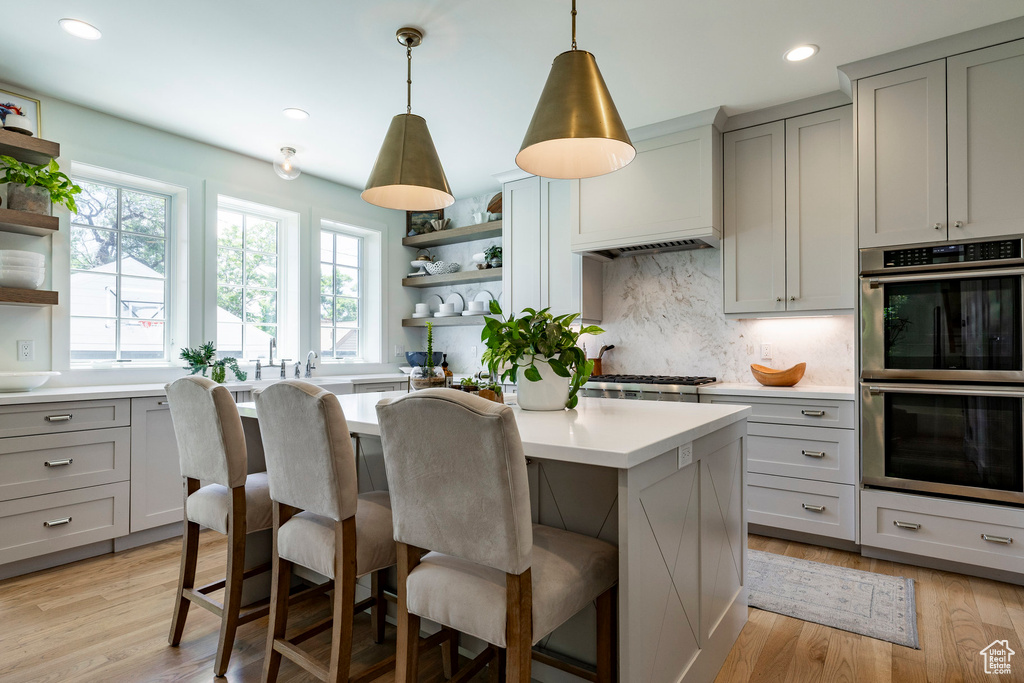 Kitchen with open shelves, appliances with stainless steel finishes, gray cabinetry, light countertops, and tasteful backsplash
