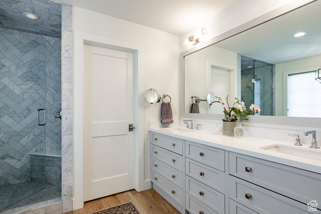 Full bath with a shower stall, double vanity, and wood finished floors