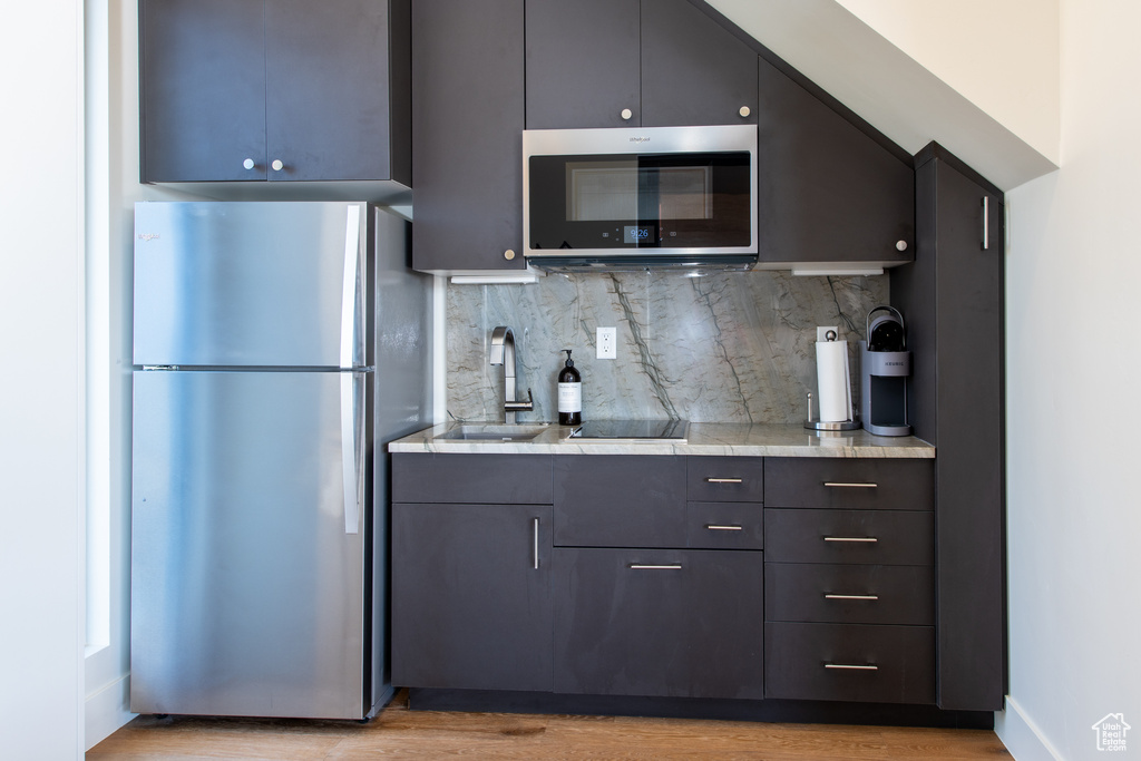 Kitchen with appliances with stainless steel finishes, light countertops, backsplash, and light wood-style flooring