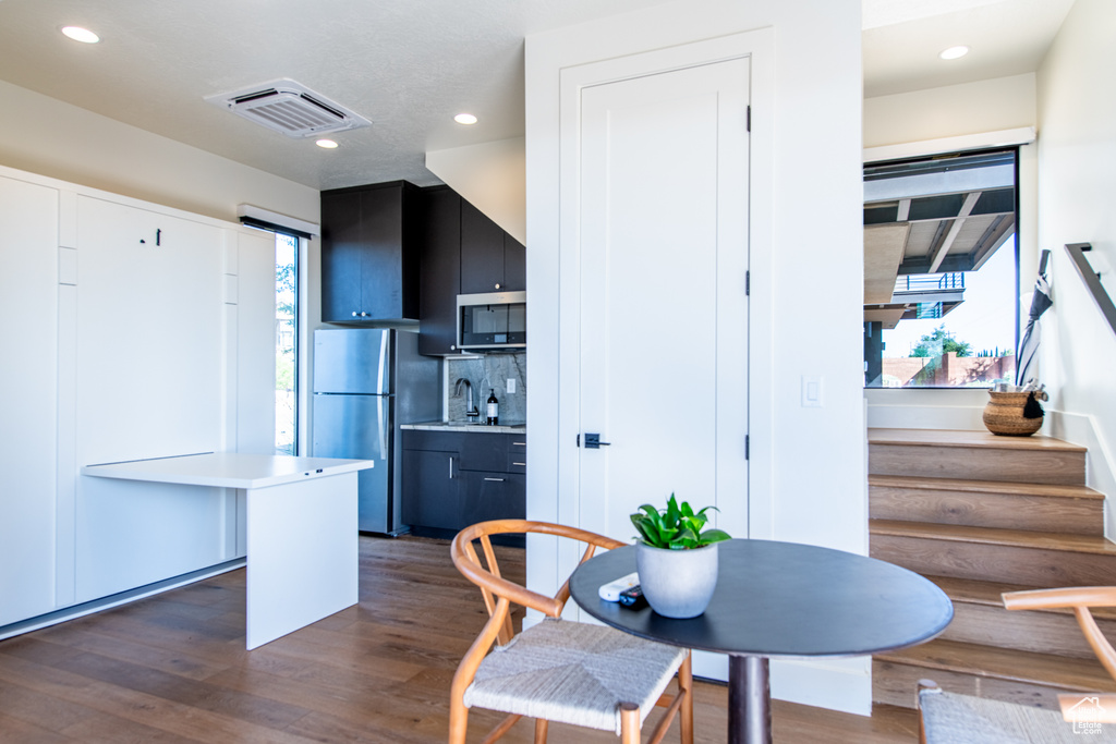 Dining space with dark wood-style flooring, stairway, and recessed lighting
