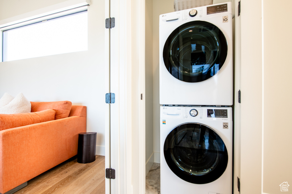 Laundry room with stacked washer / drying machine and light wood-style floors