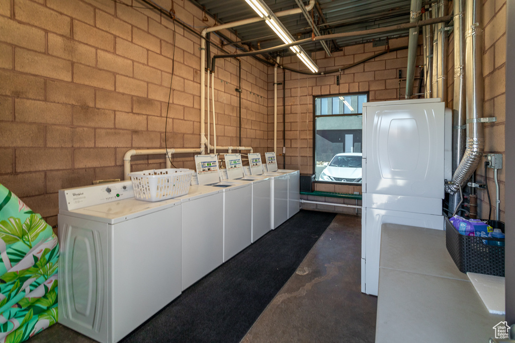 Laundry room featuring independent washer and dryer and concrete block wall