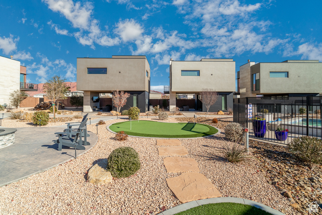 Back of property with a putting green, a patio area, and stucco siding