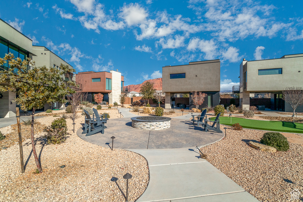 Surrounding community with an outdoor fire pit, a patio, a putting green, and a residential view