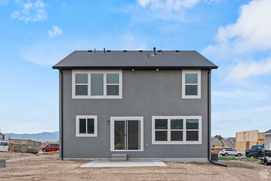 Back of house with a mountain view, stucco siding, and a patio area