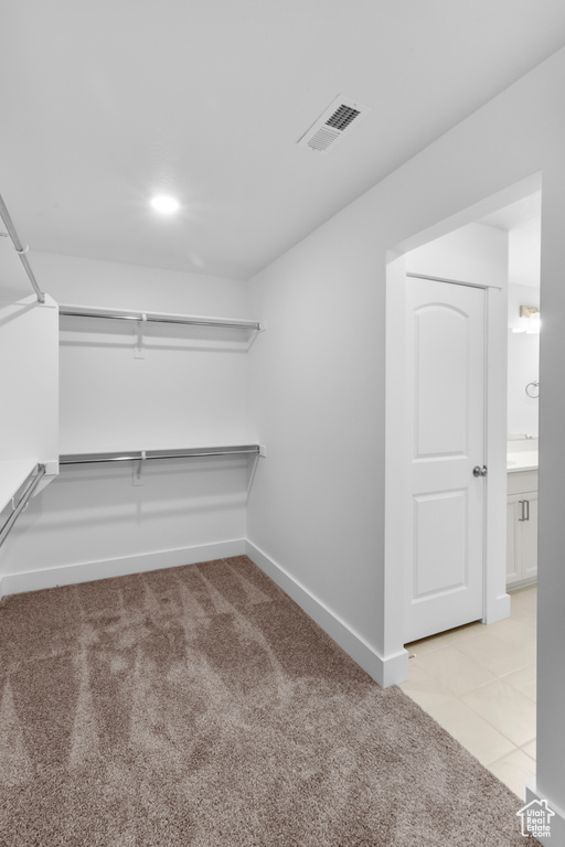 Spacious closet with light colored carpet and light tile patterned floors