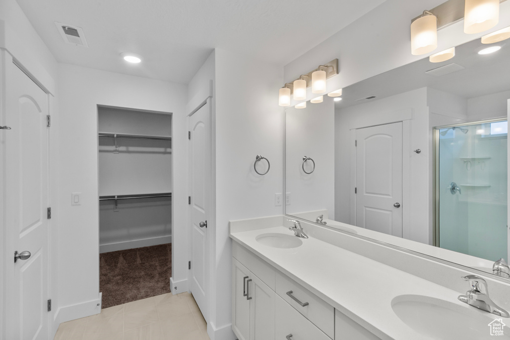 Bathroom with a shower stall, double vanity, tile patterned flooring, and a spacious closet